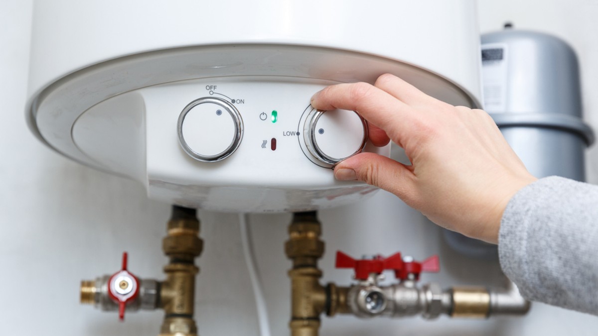 Diferența dintre boiler și instant electric - Imagine cu mâna unei femei care reglează temperatura la un aparat de încălzire