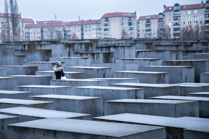 24 January 2022, Berlin: A young woman stands in the field of stelae of the Holocaust Memorial ahead of International Holocaust Remembrance Day on 27 January to commemorate the millions of Jews murdered under National Socialism and the Liberation of the Auschwitz-Birkenau Concentration Camp. Photo: Carsten Koall/dpa