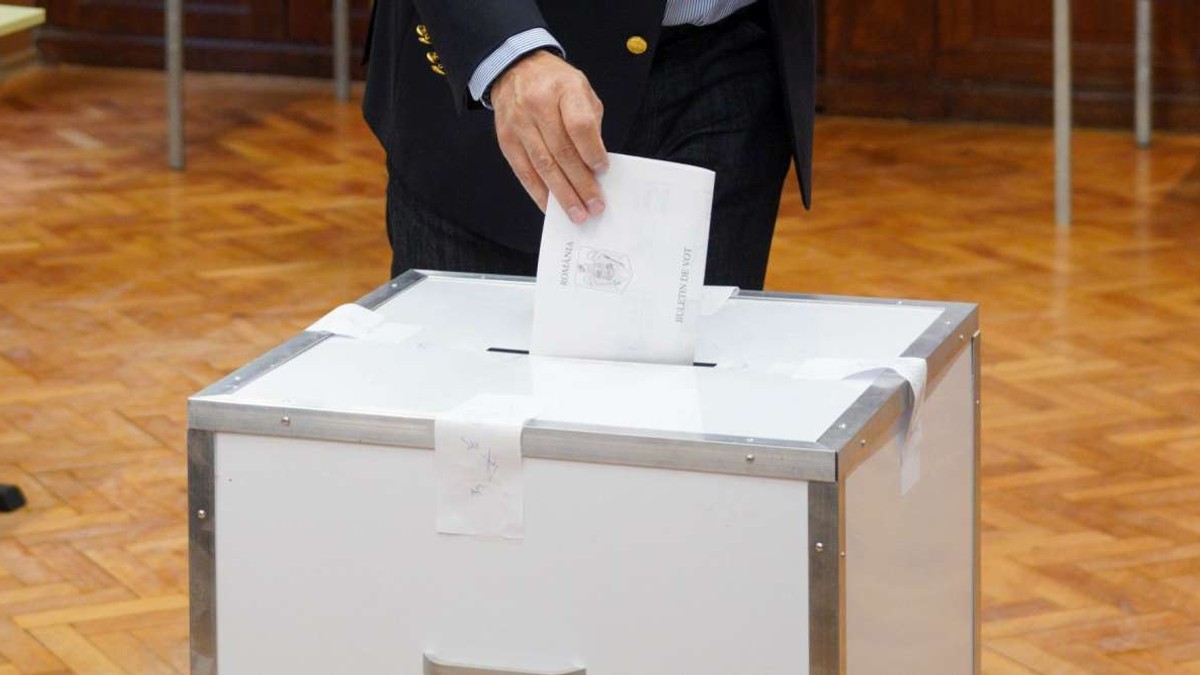 Alegător care introduce buletinul în urna de vot