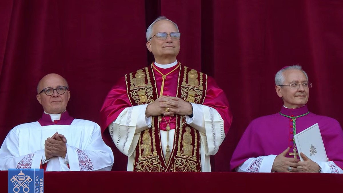 Robert Francis Prevost, noul Papă, iese la balcon îmbrăcat în straiele papale, cu două persoane de-a stânga și de-a dreapta sa.