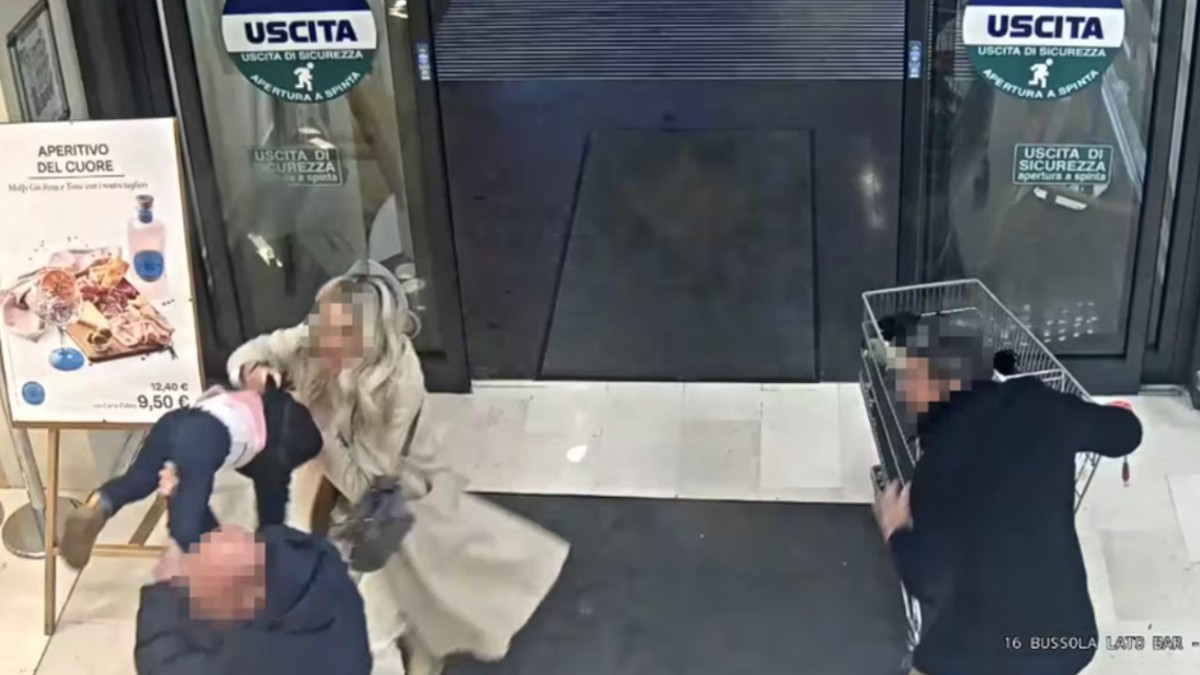 Imaginea, surprinsă de o cameră de supraveghere la ieșirea dintr-un magazin, arată un bărbat care ridică brusc un copil mic, în timp ce o femeie intervine imediat pentru a-l opri.