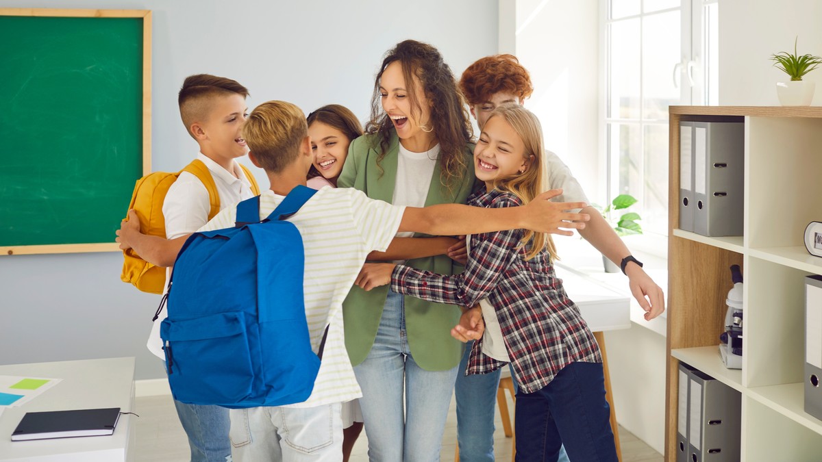 Elevi fericiți, alături de învățătoarea lor. Poză cu caracter ilustrativ. Foto: Shutterstock