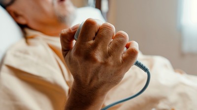 Imagine ilustrativă cu un bolnav aflat pe patul de spital care apasă butonul de panică