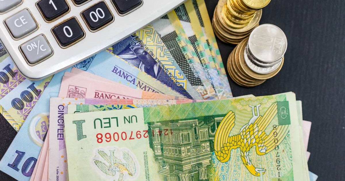 Mai multe bancnote românești de câte un leu, 10 lei și 100 de lei care stau pe masă