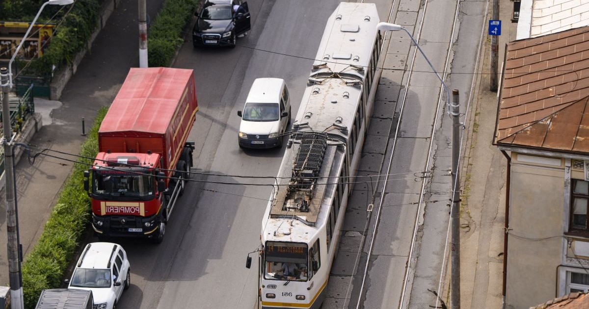 Tramvai în trafic merge pe șina lui, flancat de mai multe vehicule aflate pe șosea