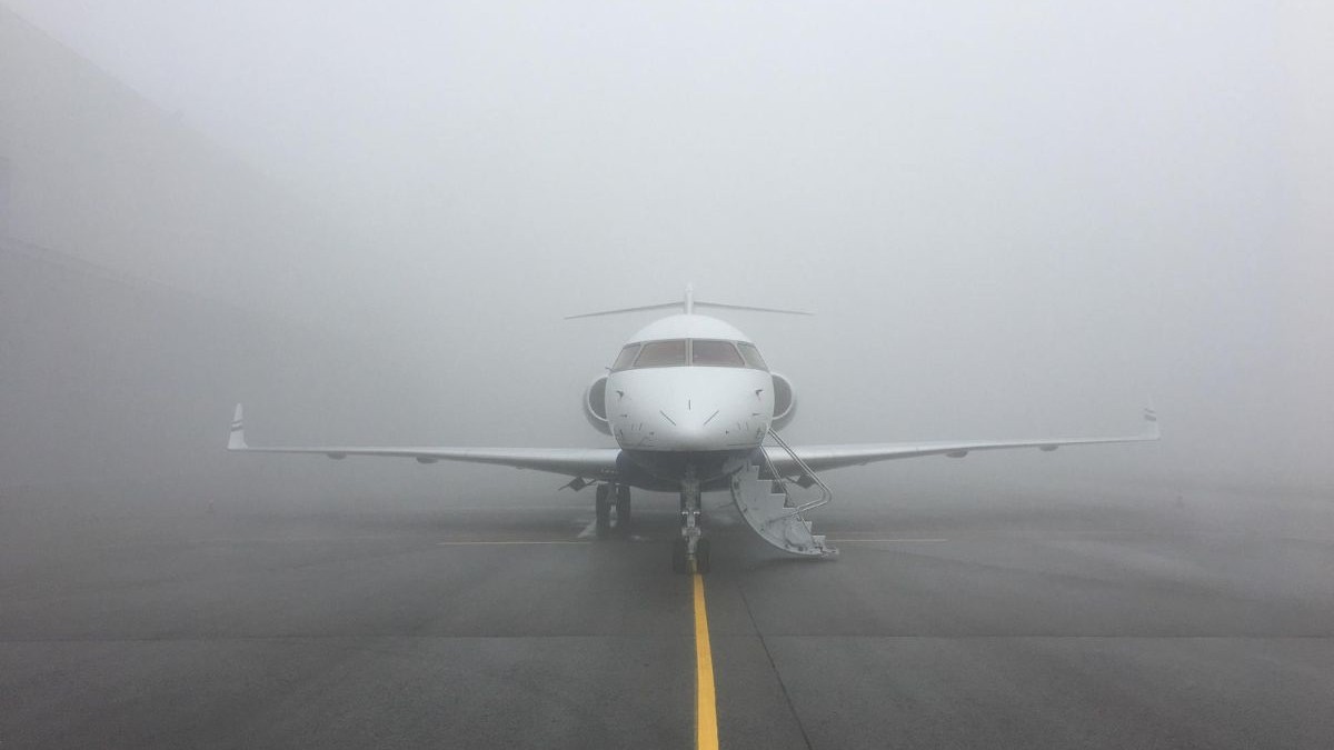 avion pe pista de decolare, înconjurat de ceață densă