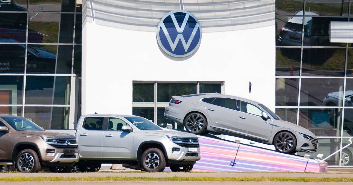 mașini Volkswagen noi, prezentate in fata fata unei clediri cu sigla VW