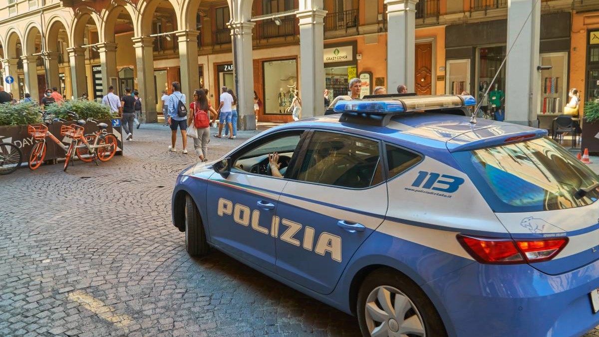 masina de politie italia, pe un drum pietonal acoperit cu piatra cubica, se observa spatiul amenajat al unui restaurant