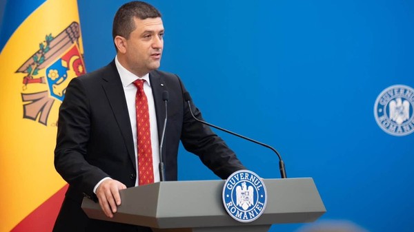 Ministrul interimar al Apărării, Radu Miruță, în timpul unei conferințe de presă la Guvernul României. Poartă un costum negru, o cămașă labă și o cravată roșie