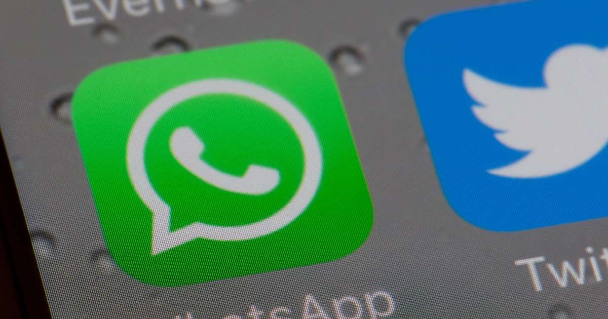 Logo-ul aplicației WhatsApp, pe un ecran de iPhone, lângă logo-ul aplicației Twitter, pe un fundal gri.