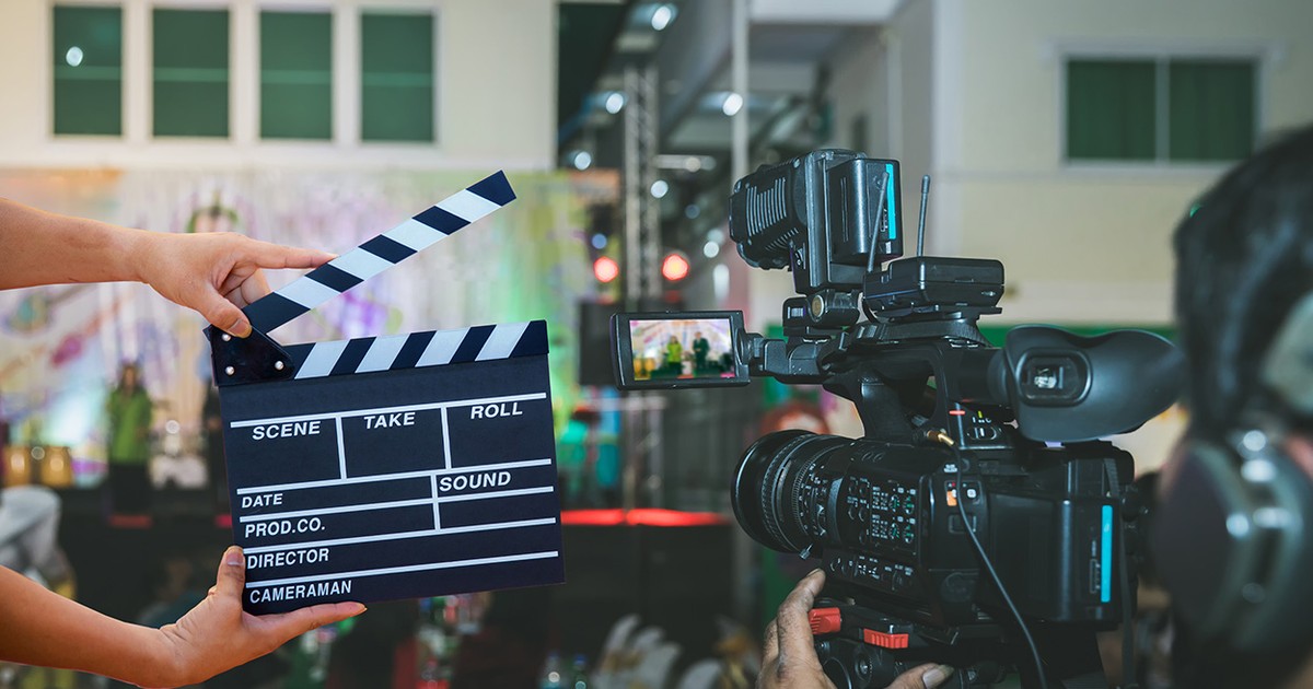 Imagine de pe platourile de filmare cu o cameră care filmează și o clachetă pe care scrie scena la care s-a ajuns.