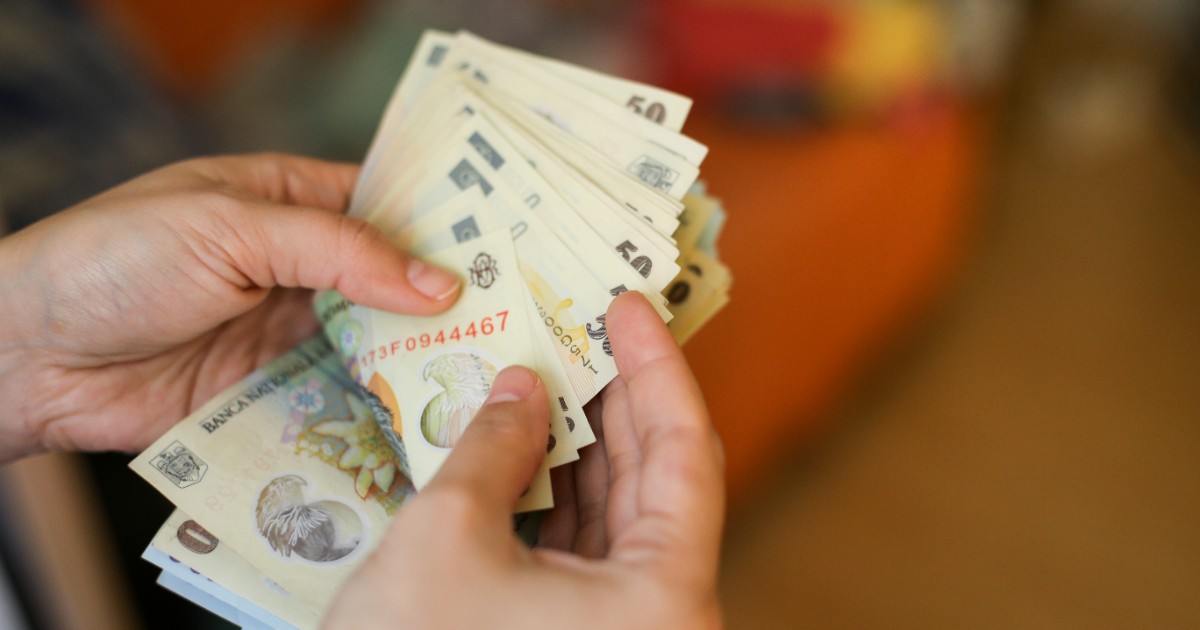 Un bărbat în timp ce numără mai multe hârtii de câte 50 de lei