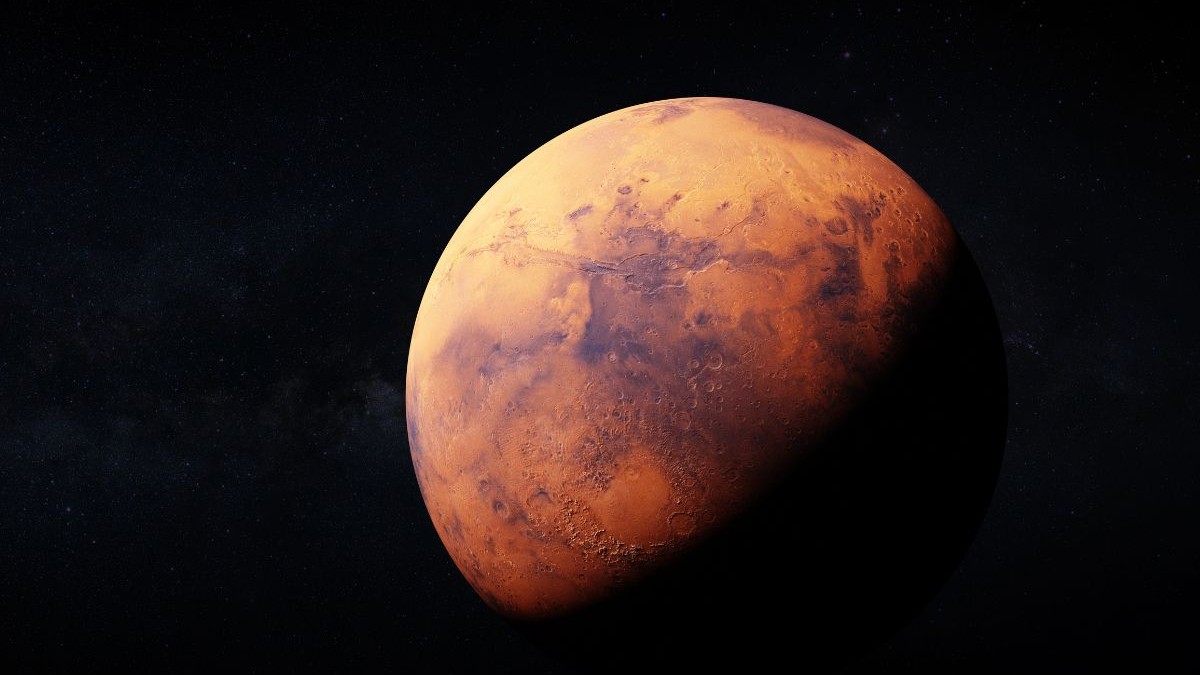 randare realistica a planetei Marte. jumătatea de sus a planetei are o culoare roșie și este luminată iar jumătatea de jos apare întunecată. fundal imaginii este negru