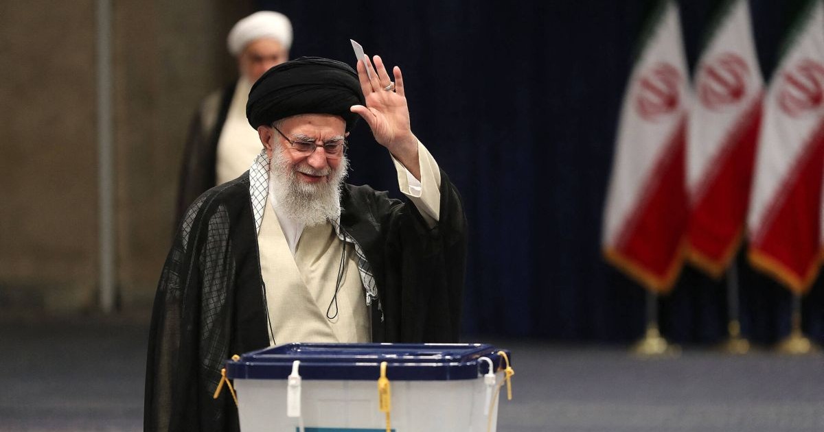 Cu brațul stâng ridicat, ayatollahul Ali Khamenei îi salută pe cei prezenți după ce și-a exprimat votul pentru alegerile prezidențiale anticipate de la Imam Khomeini Husseiniya din Teheran, Iran, 28 iunie 2024