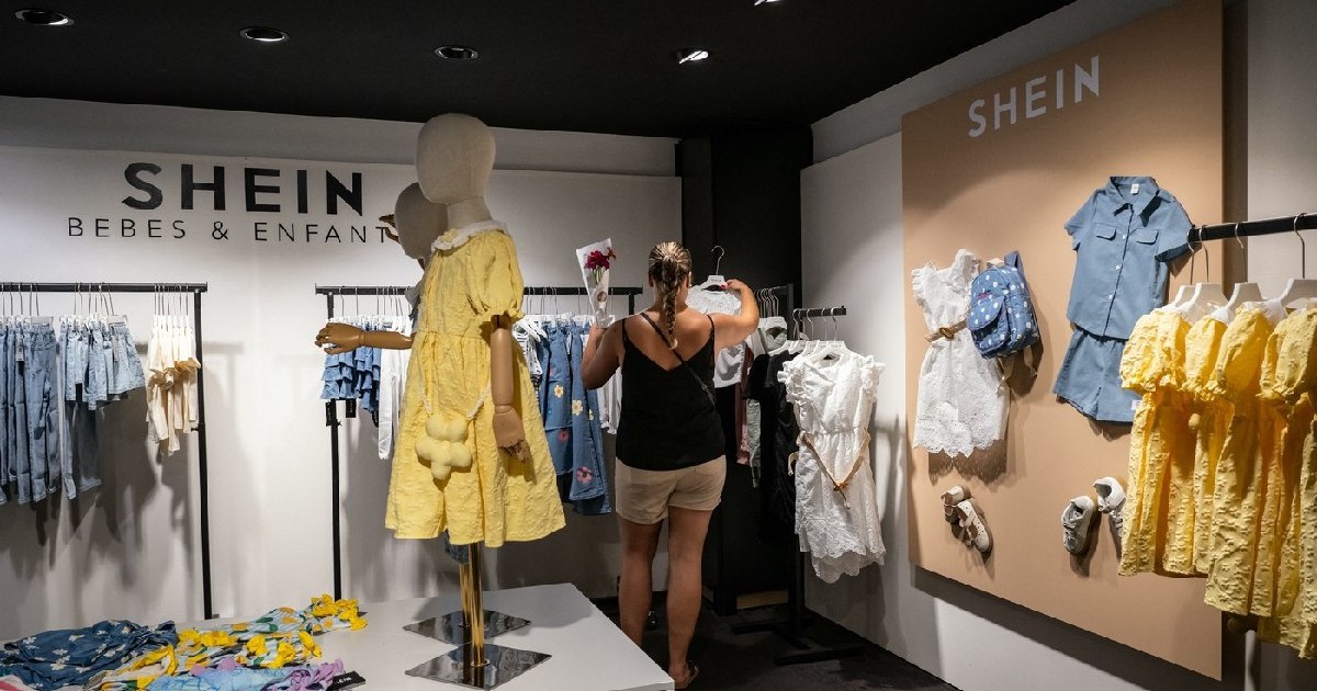 Un client se uită la haine la un magazin pop-up al brandului de modă rapidă Shein, în Dijon, pe 26 iunie 2025.