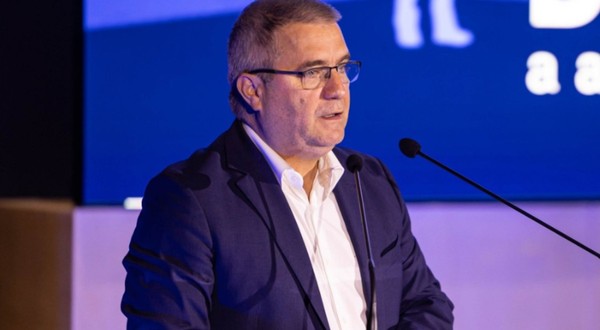  Sorin Gabriel Ionescu în costum albastru închis și cămașă albă, în timp ce vorbește la microfon