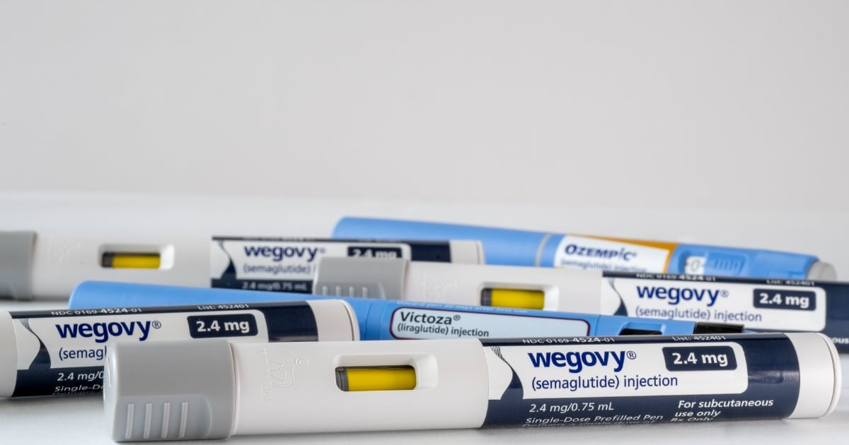 Mai multe dispozitive de injectare pentru medicamentul Wegovy sunt aranjate pe o suprafață albă, alături de alte produse similare. Imaginea evidențiază tratamente utilizate în gestionarea greutății și a afecțiunilor metabolice.