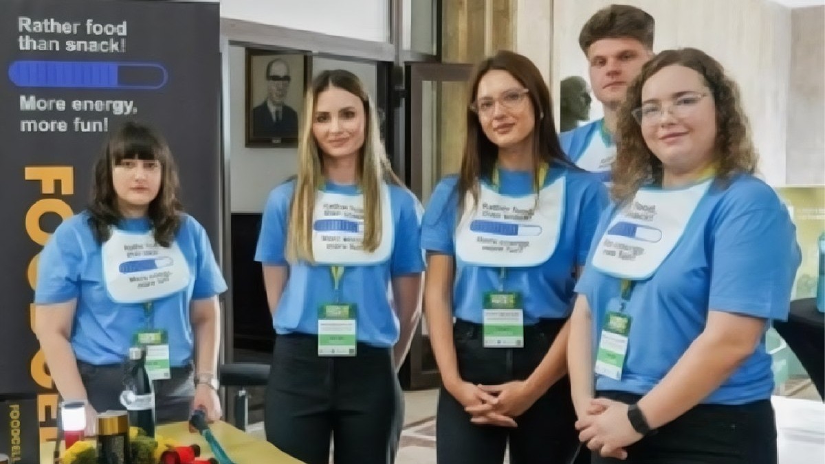 Cinci tineri cu tricouri albastre și pantaloni negri prezinta biscutii proteici Foodcell
