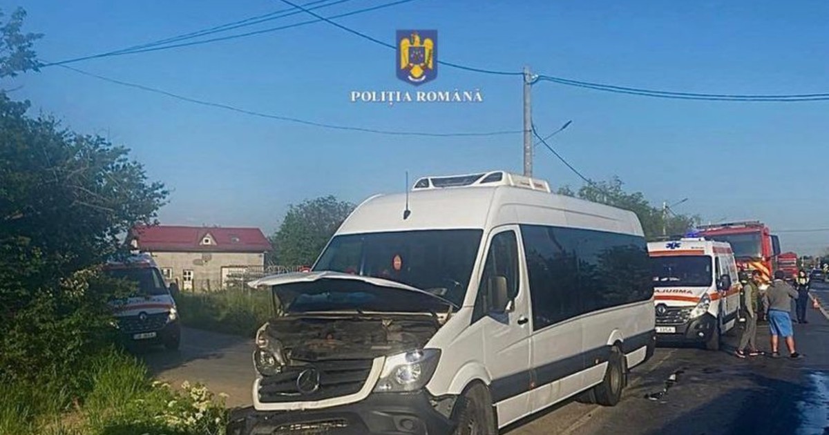 Un microbuz avariat în accident, pe o șosea. În spate sunt ambulaanțe și mașini de pompieri