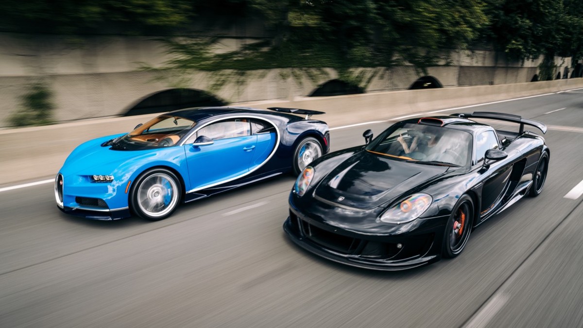 Un bugatti albastru și un porsche negru pe o șosea