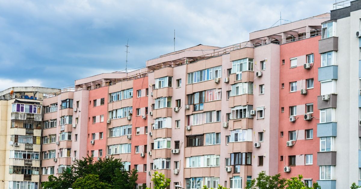 Mai multe blocuri de apartamente, cu fațade de culoare roz și crem, în București, cu copaci cu frunze verzi în față, în anul 2020