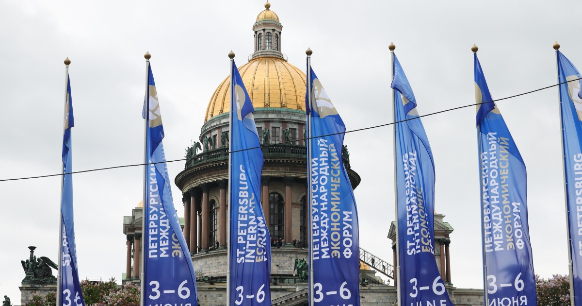În imagine apar bannerele Forumului Economic Internațional de la Sankt Petersburg, amplasate în fața impunătoarei Catedrale Sfântul Isaac, unul dintre simbolurile orașului. Steagurile albastre anunță ediția din 2026 a evenimentului, considerat unul dintre cele mai importante forumuri economice organizate de Rusia.