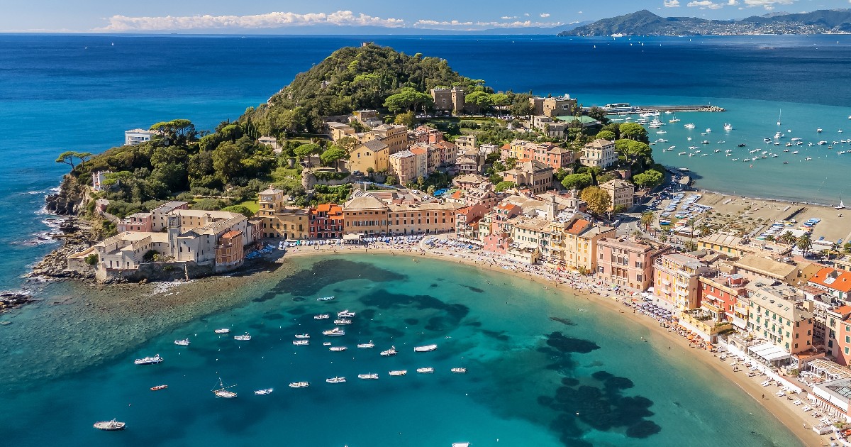 O vedere aeriană spectaculoasă surprinde peninsula Sestri Levante din Italia, cu clădiri colorate în stil ligurian flancate de apele turcoaz ale Golfului Tăcerii și ale Golfului Basmelor.