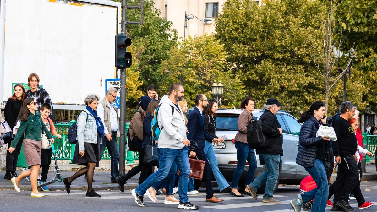 Mai mulți oameni traversează o stradă din București