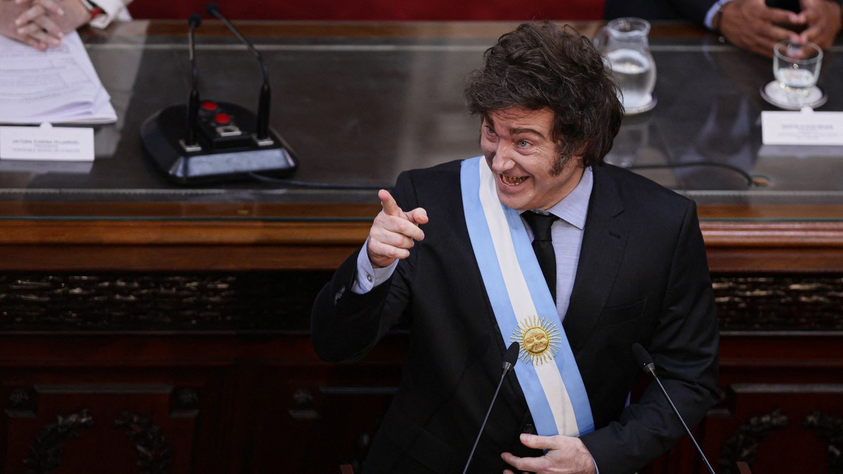 Javier Milei, președintele Argentinei, cu un steag al țării peste costum, arătând cu degetul
