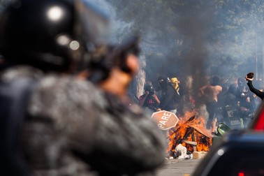 epa04251696 Members of the Brazilian police confront a group of demonstrators that burn a barricade during a protest against the FIFA World Cup 2014 in Sao Paulo, Brazil, on 12 June 2014. Demonstrators clashed with police Thursday in Sao Paulo, just a few hours before the World Cup opening game between hosts Brazil and Croatia was due to start in the city's Arena Corinthians. EPA/Marcos Mendez