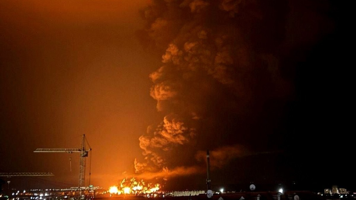 Imaginea dramatică, realizată noaptea, surprinde un incendiu masiv sau o explozie, dominată de o flacără intensă și un nor uriaș de fum de culoare portocaliu-roșiatic. Scena sugerează un incident major, probabil la o instalație industrială sau portuară (judecând după o macara vizibilă în stânga) în Feodosia, Crimeea.