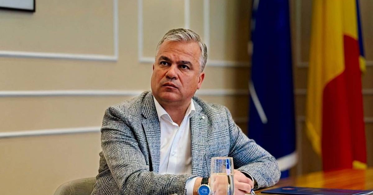 Adrian Veștea într-un costum gri, la un birou