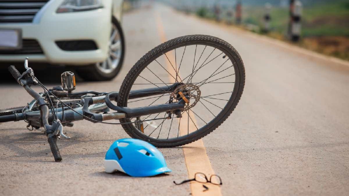 Accident între un autoturism și o bicicletă. Vehiculul cu două roți este căzut pe stradă, alături fiind o cască de protecție și o pereche ruptă de ochelari