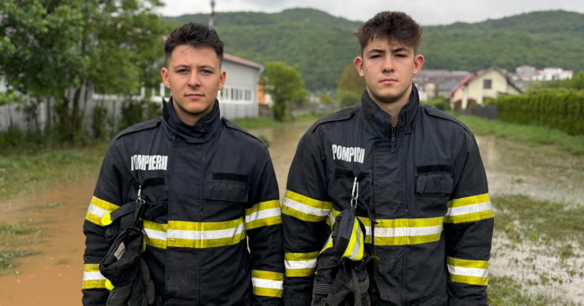 În imagine sunt ilustrați doi tineri îmbrăcați în uniformă de pompieri