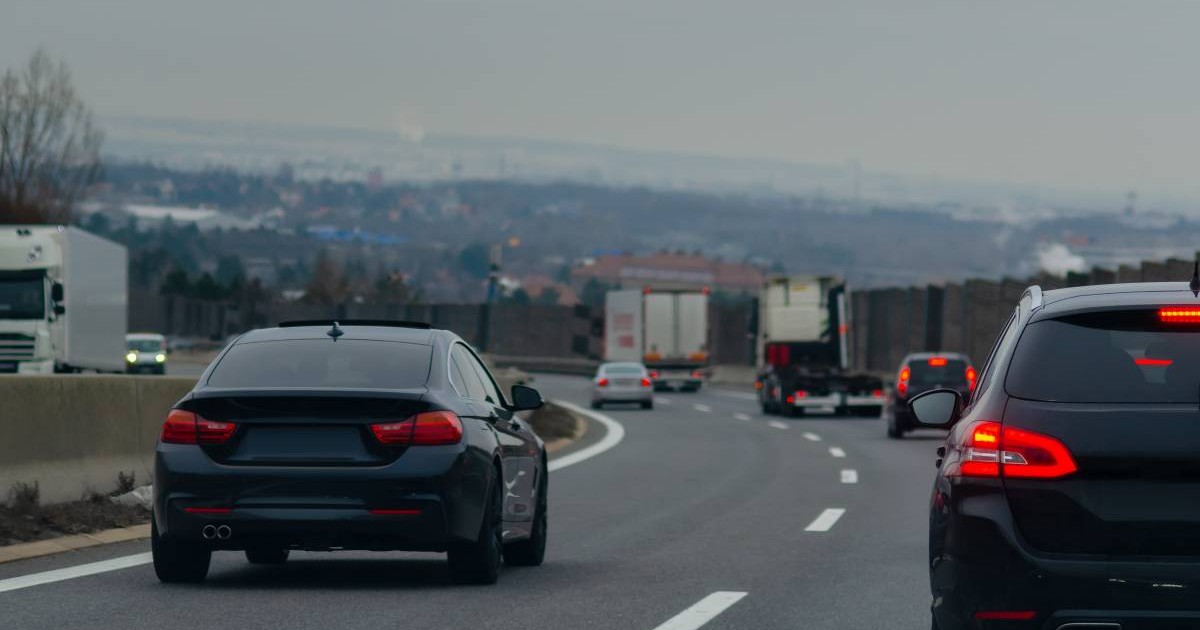 Autotradă aglomerată cu două benzi pe sens desparțite de un parapet.În prim plan sunt doua mașini negre, una care circulă pe banda doi, iar cealaltă pe banda unu.