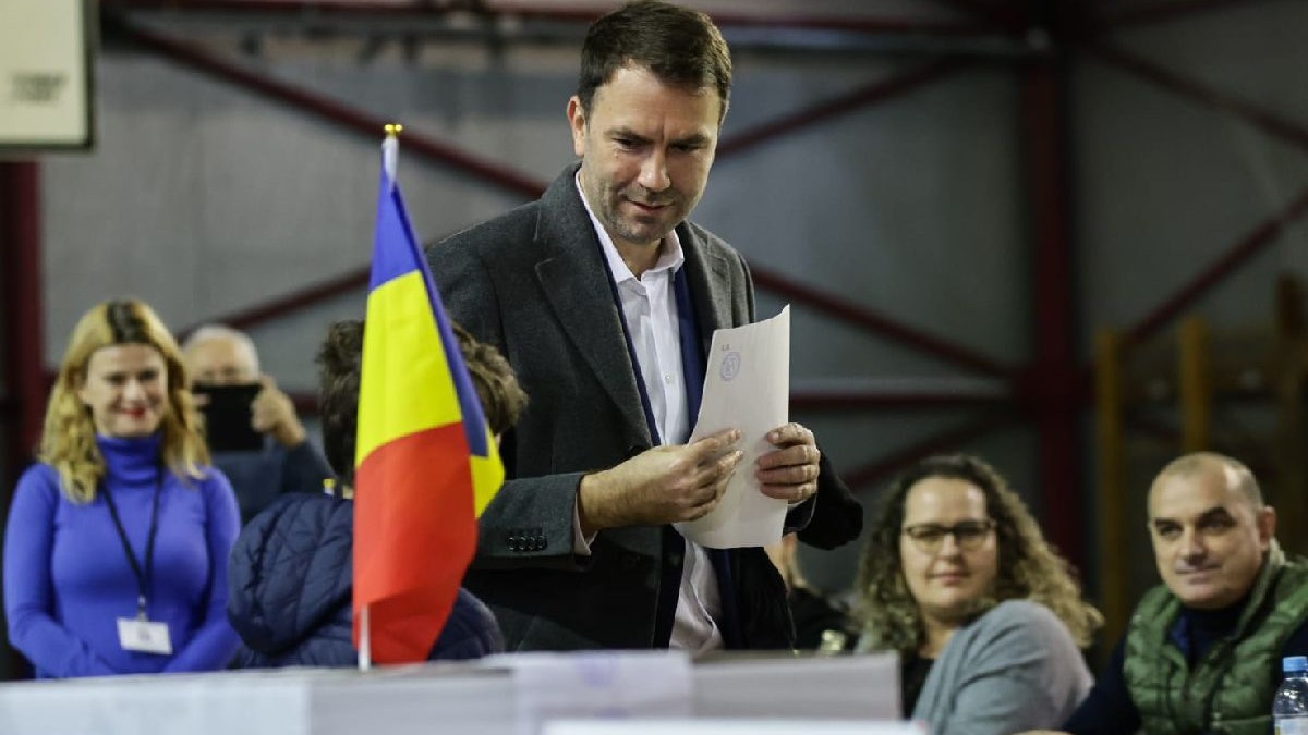 Fotografie cu Cătălin Drulă îmbrăcat într-un costum gri care votează într-o sală de sport