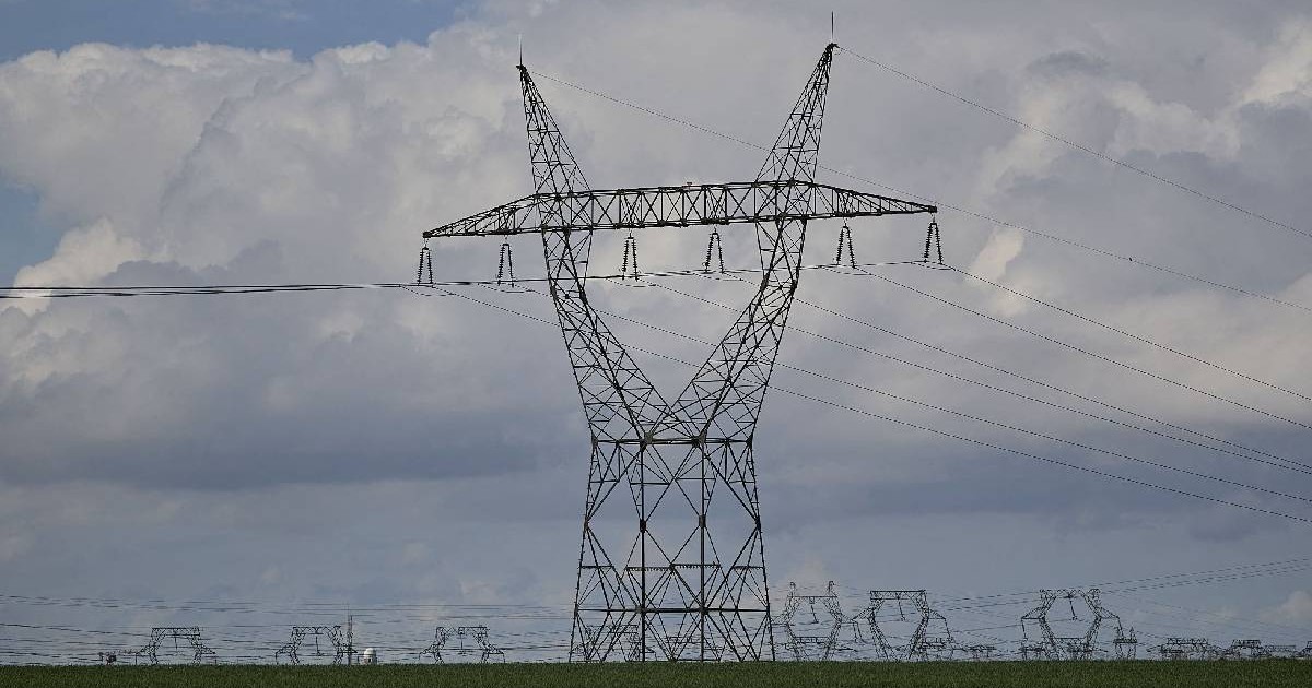 Un stâlp de curent electric masiv, din metal, aflat pe un câmp