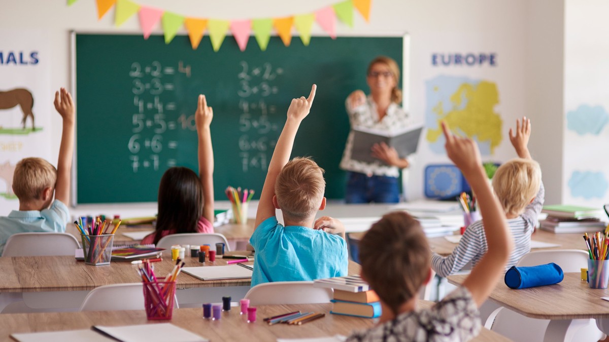Reducei la rechizite şcolare în oferta de PC Garage - Imagine cu o o profesoară şi elevii ei într-o sală de clasă