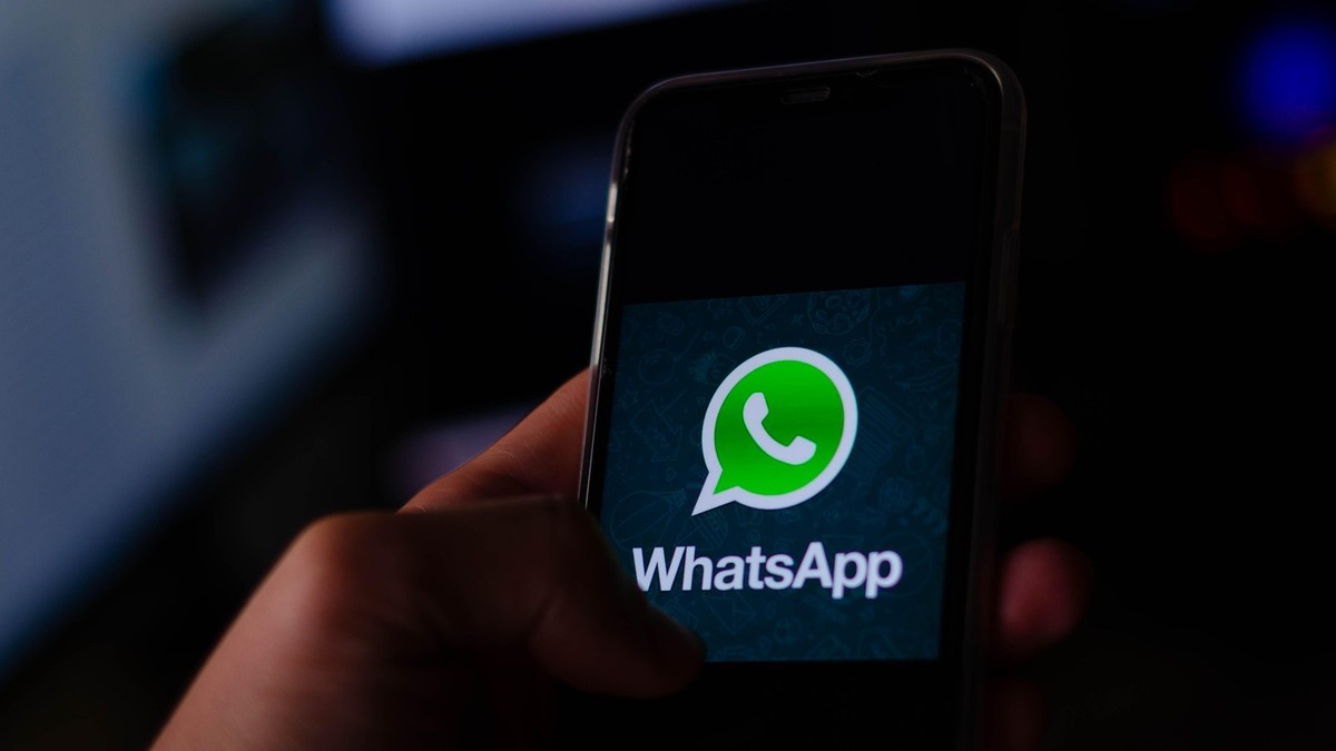 Persoană care ține în mâini un telefon mobil, iar pe ecran este logo-ul Whatsapp