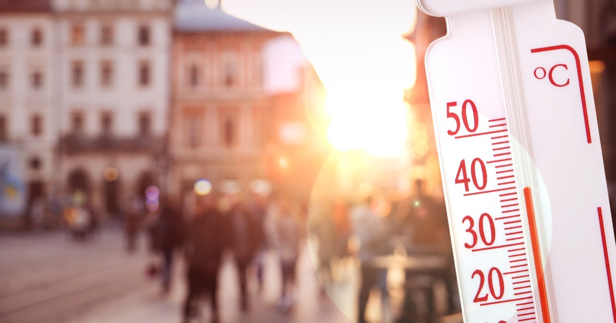 Imaginea prezintă un termometru alb ce indică peste 35°C, suprapus peste imaginea estompată a unei piețe urbane însorite și aglomerate.