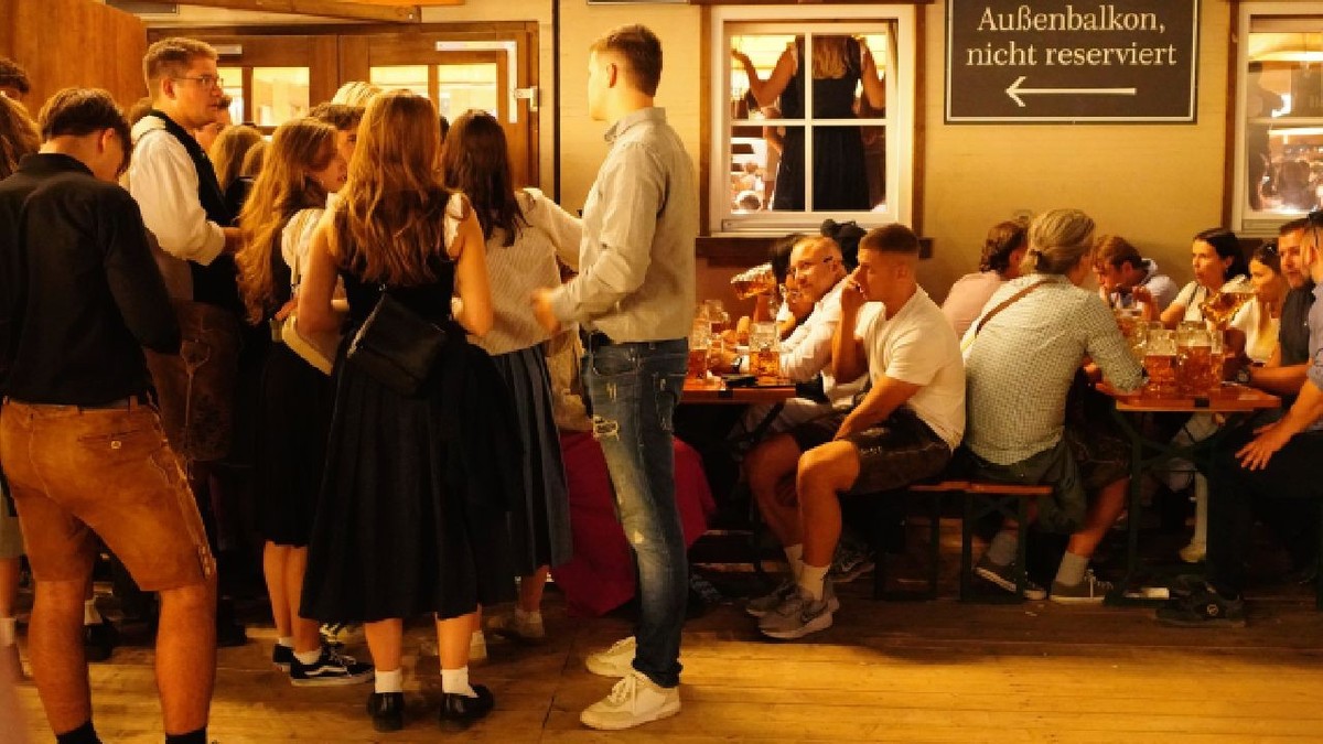 Oamenii se distrează la Oktoberfest 2026. În imagine, mai multe grupuri de tineri, băieți și fete, în fața unui local