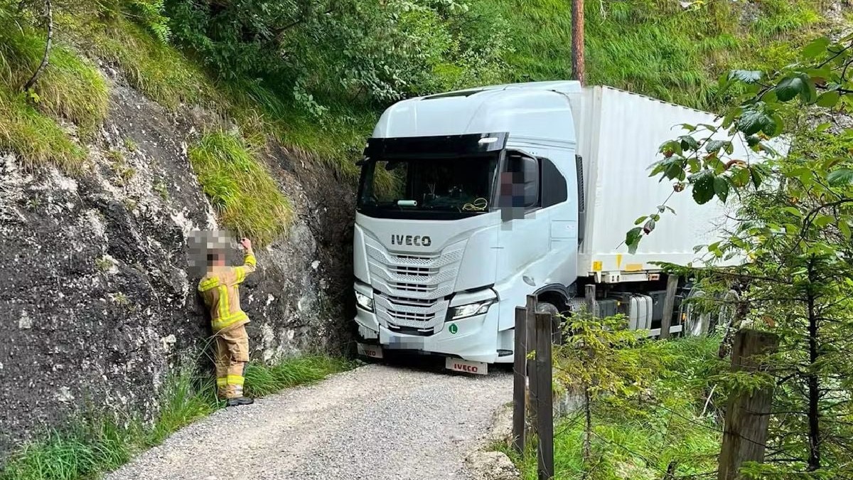 Un TIR alb blocat pe un drum forestier, dirijat de un pompier