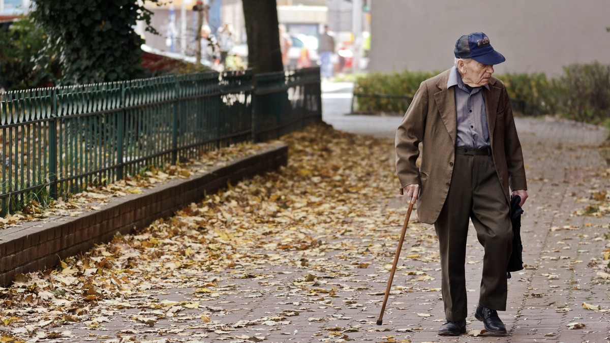 Adevărul despre pensionarea la 70 de ani. Patru lucruri care se dezbat în societate în același timp și care ascund adevărata problemă. Pensionar în baston plimbându-se printr-un parc cu frunze pe jos