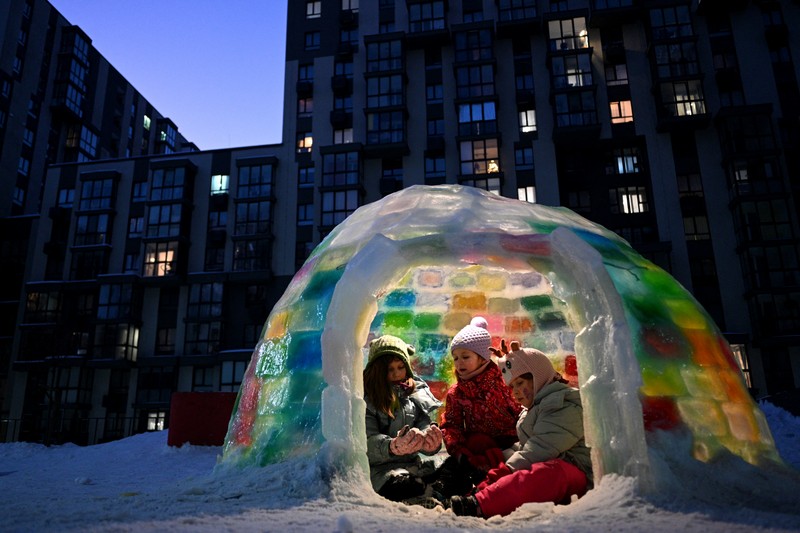 Copiii se joacă în interiorul unui iglu de gheață construit de oamenii din zonă în curtea unui bloc din Lviv, pe 18 ianuarie 2026. Foto: AFP