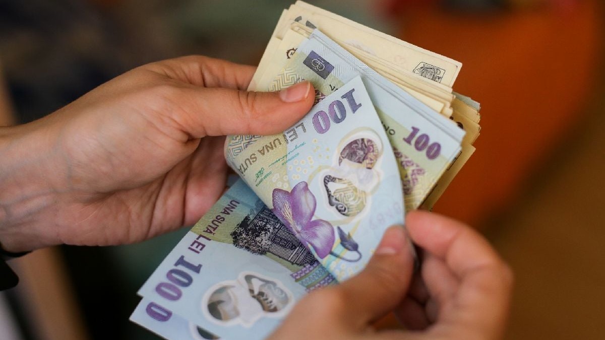 Imaginea prezintă mâinile unei persoane care numără un teanc de bancnote românești de 100 de lei.