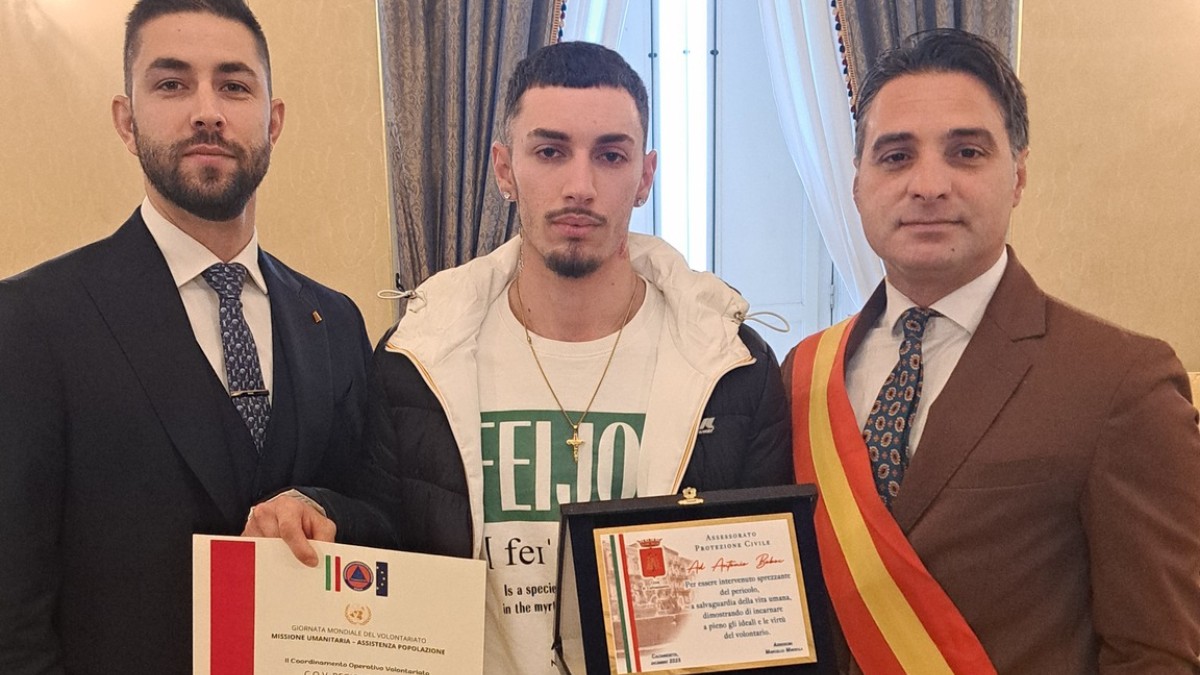 Tânărul român Antonio alături de autoritățile locale, în timp ce ține în mână o placă prin care este premiat și un certificat