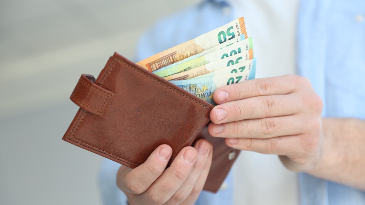 Un bărbat care scoate bancnote de euro din portofel