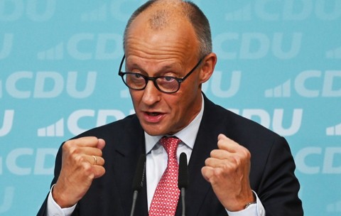 Cancelarul german Friedrich Merz vorbind gesticulând cu ambii pumni strânși în fața unui fundal cu sigla partidului CDU
