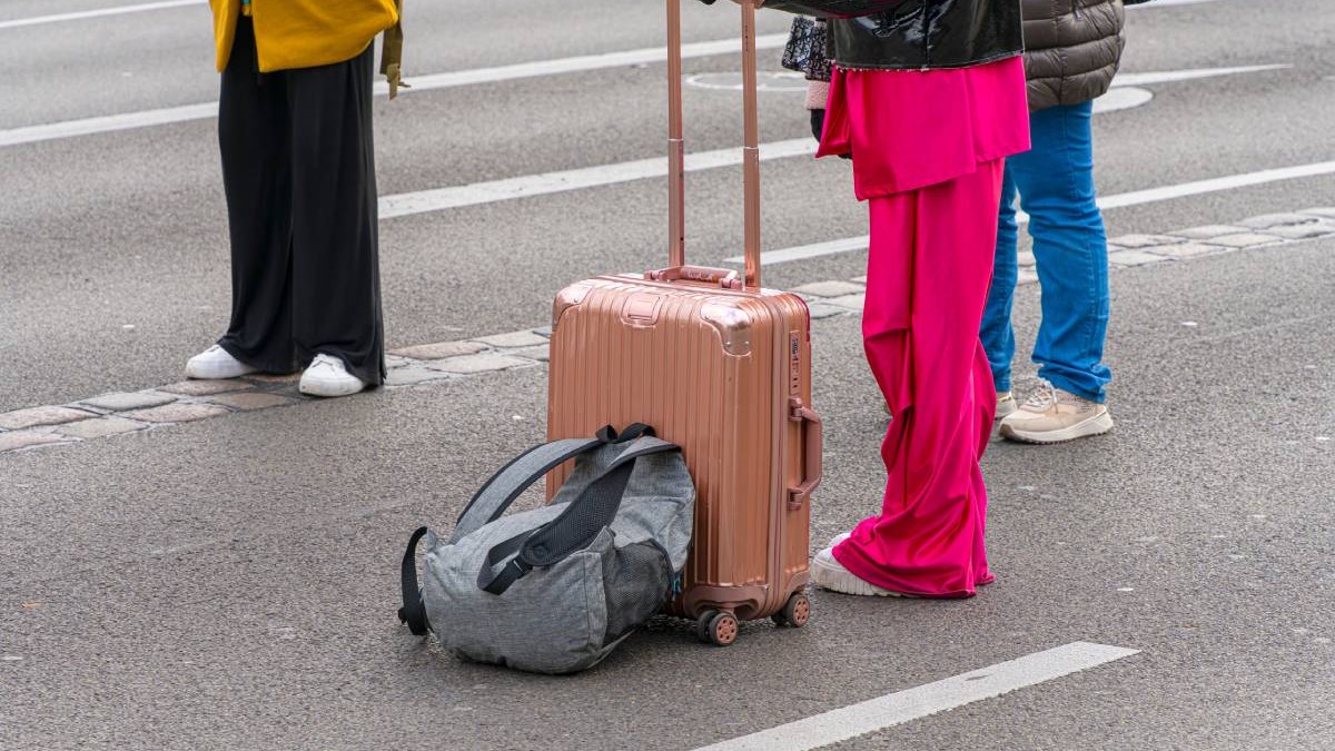 Trei persoane în aeroport cu un troller mic și un bagaj de mână