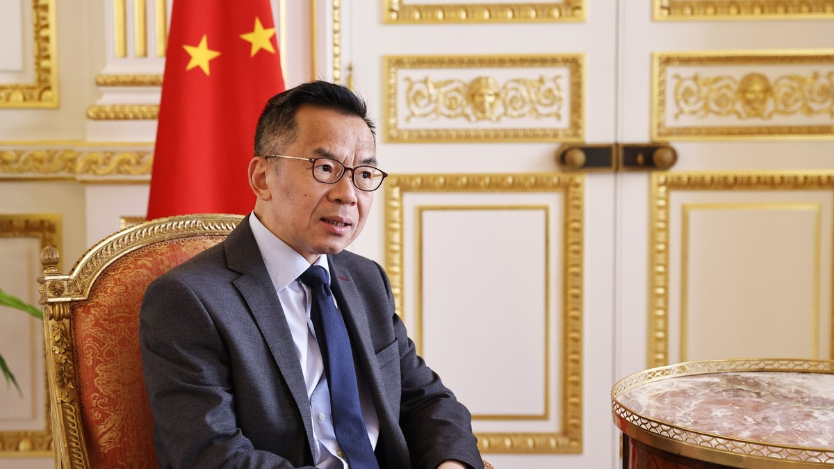 Lu Shaye surprins în timp ce stă pe scaun și având în spatele său steagul Chinei